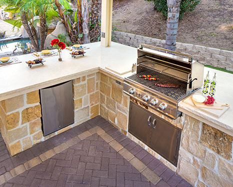 tan stone brick outdoor kitchen with kebab on grill