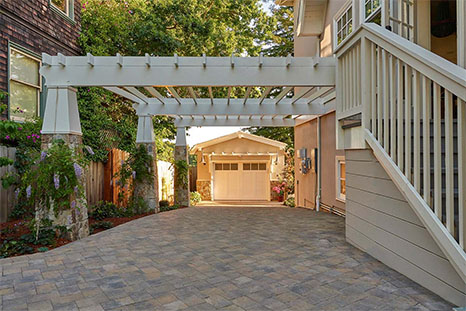 large driveway with gray and tan pavers and a white overhang