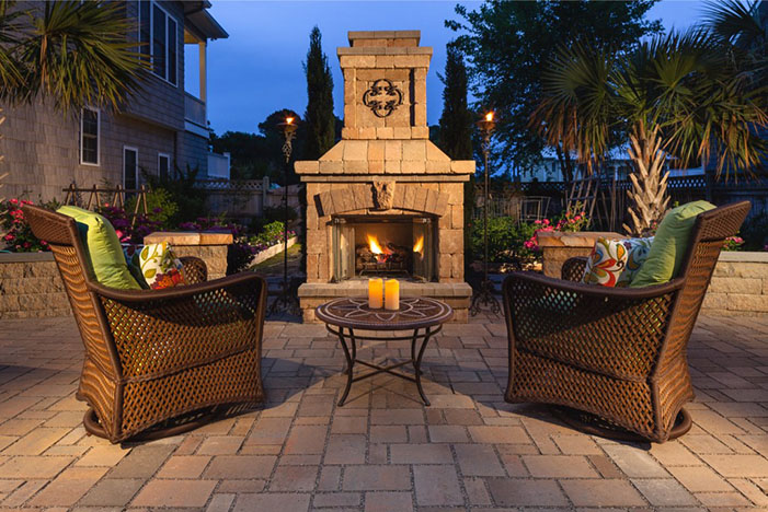 lit outdoor fire place with two chairs in front