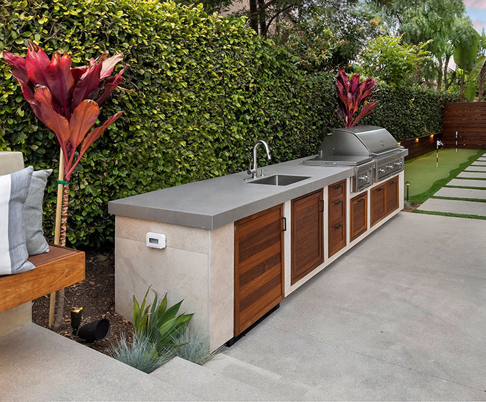 outdoor kitchen with grill against wall of plants