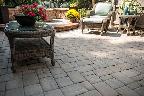 patio pavers with table to left and fire pit in background