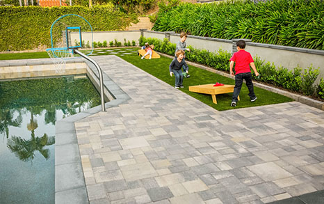 large gray paver pool deck with children playing