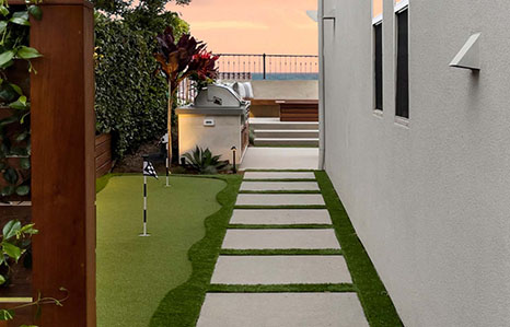 paver slabs next to mini golf leading to outdoor modern minimal kitchen in coastal home