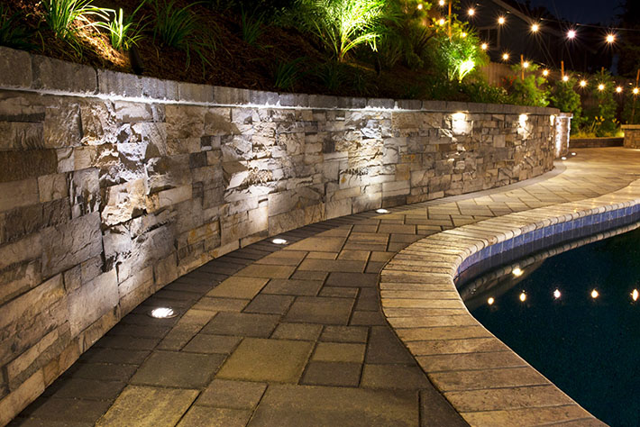 curved pool deck with paver wall behind it.